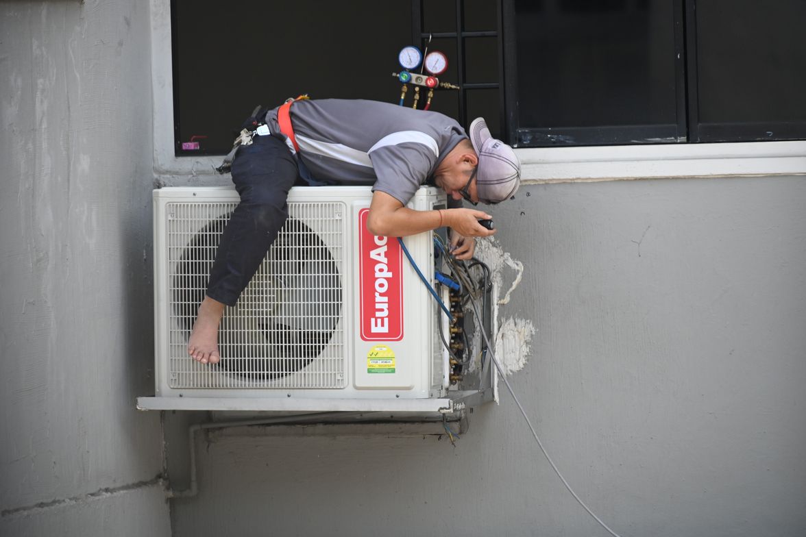 Technician servicing a wall-mounted ductless air conditioning unit.