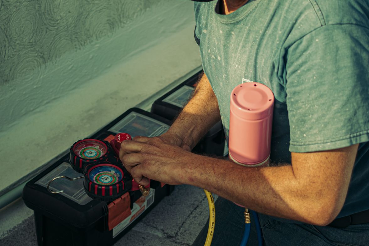 Technician kneeling beside an outdoor HVAC unit during an equipment installation.
